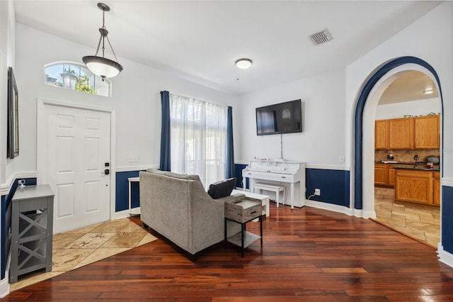 living area with hardwood / wood-style flooring, arched walkways, and baseboards