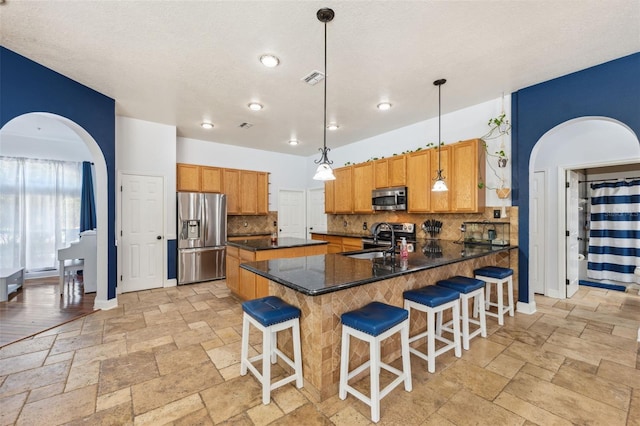 kitchen with appliances with stainless steel finishes, a sink, decorative backsplash, stone tile flooring, and recessed lighting