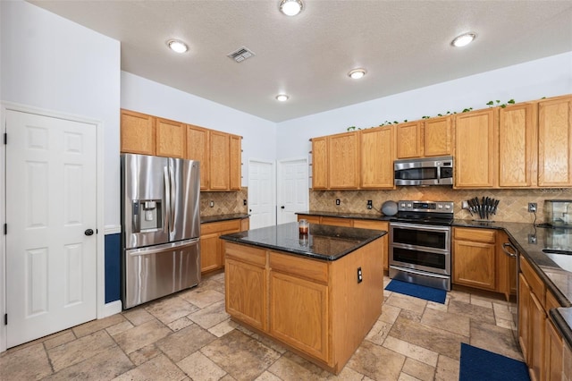 kitchen with appliances with stainless steel finishes, stone tile floors, a kitchen island, backsplash, and recessed lighting