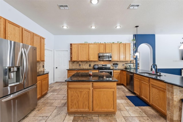 kitchen featuring stainless steel appliances, a sink, stone tile flooring, arched walkways, and recessed lighting