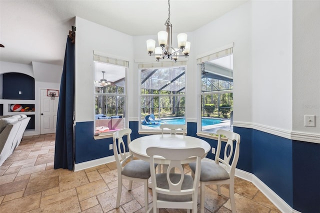 dining area with stone tile flooring, a chandelier, baseboards, and a sunroom