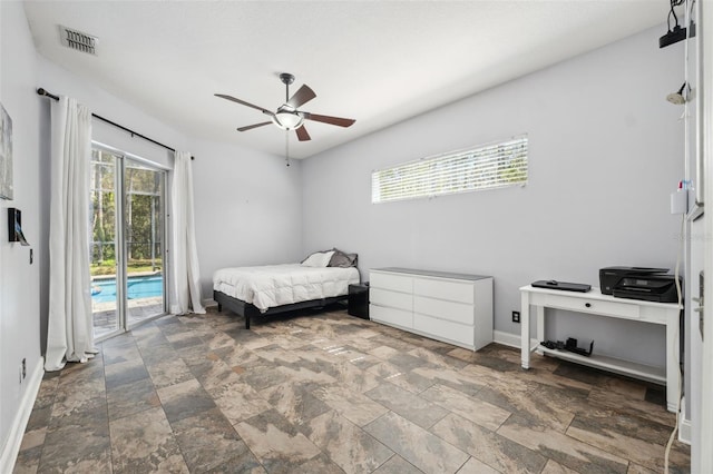 bedroom featuring access to outside, multiple windows, stone finish floors, and baseboards
