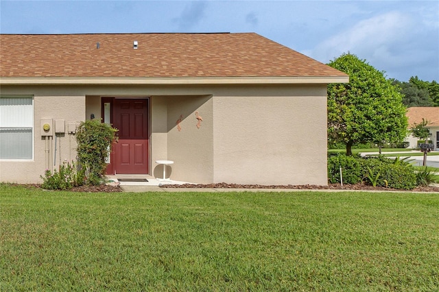 11158 Heathrow Ave, Spring Hill, FL 34609 - view of exterior entry featuring roof with shingles, stucco siding, and a lawn