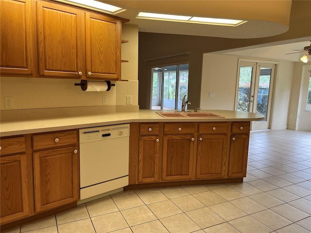 10054 Hernando Ridge Rd, Weeki Wachee, FL 34613 - kitchen with white dishwasher, a sink, a peninsula, brown cabinetry, and light tile patterned floors