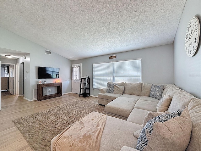 living area featuring lofted ceiling, light wood-style flooring, a textured ceiling, and baseboards