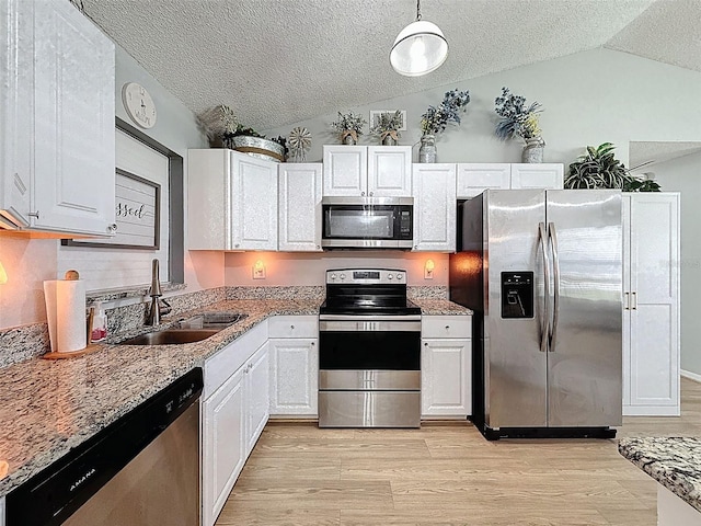kitchen featuring stainless steel appliances, lofted ceiling, a sink, a textured ceiling, and white cabinetry