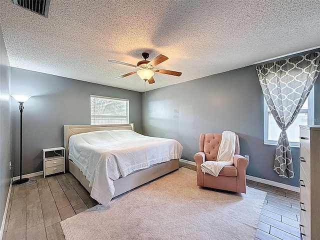 bedroom with wood finish floors, a ceiling fan, baseboards, and a textured ceiling