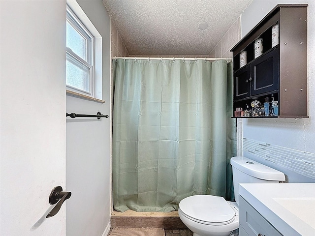bathroom featuring toilet, curtained shower, vanity, and a textured ceiling