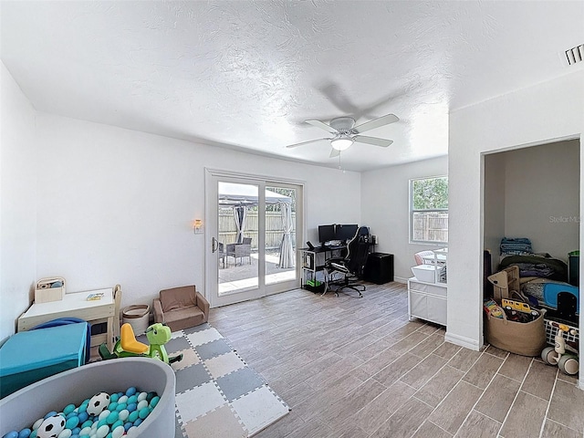 office area with a ceiling fan, wood finished floors, baseboards, and a textured ceiling