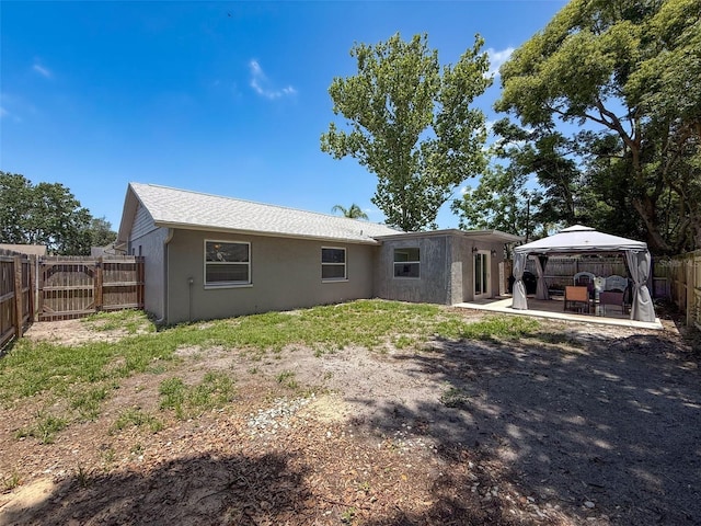 back of house featuring a gazebo, stucco siding, a fenced backyard, and a patio