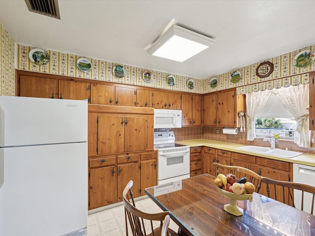 6823 Oak Hill Dr, New Port Richey, FL 34653 - kitchen featuring white appliances, a sink, wallpapered walls, brown cabinets, and light flooring