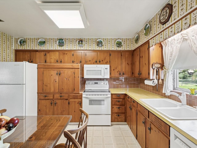 6823 Oak Hill Dr, New Port Richey, FL 34653 - kitchen featuring white appliances, a sink, wallpapered walls, brown cabinetry, and light countertops