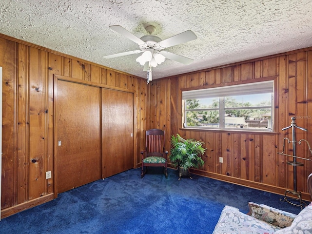 6823 Oak Hill Dr, New Port Richey, FL 34653 - sitting room featuring carpet flooring, ceiling fan, wood walls, and a textured ceiling