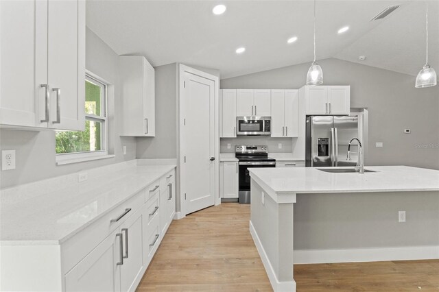 8792 N Sandree Dr, Dunnellon, FL 34434 - kitchen featuring appliances with stainless steel finishes, a sink, white cabinetry, light wood finished floors, and vaulted ceiling