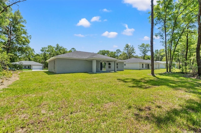 8792 N Sandree Dr, Dunnellon, FL 34434 - back of property with a yard, stucco siding, and a detached garage
