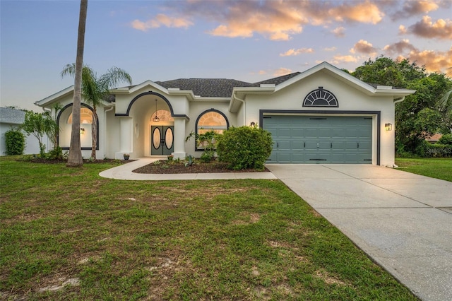 view of front of home featuring driveway, stucco siding, a yard, and an attached garage