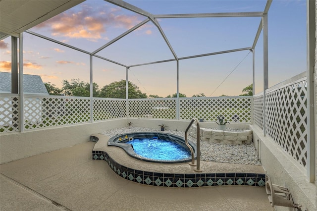 pool at dusk featuring an in-ground hot tub and a lanai