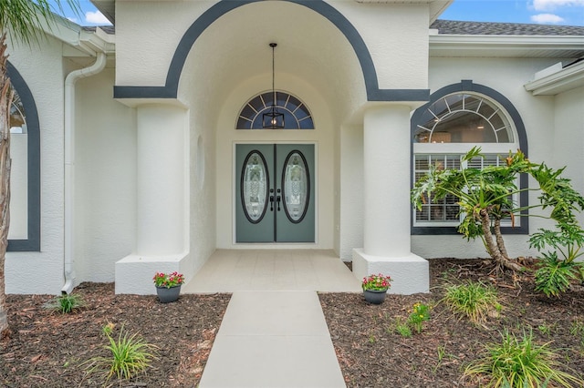 property entrance featuring stucco siding and roof with shingles