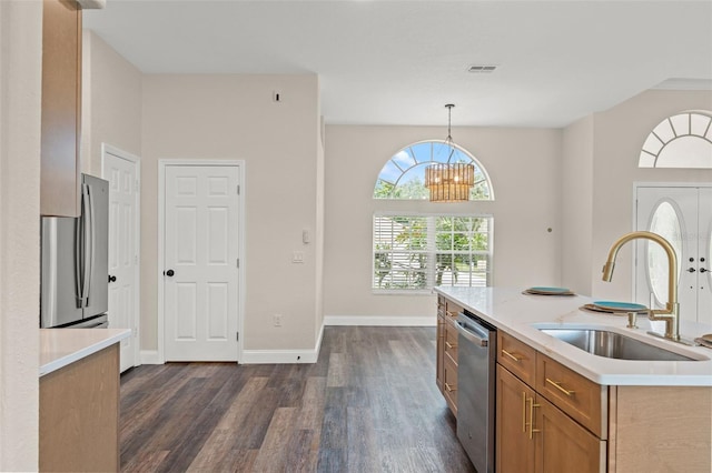 kitchen with stainless steel appliances, brown cabinetry, a sink, dark wood finished floors, and light countertops