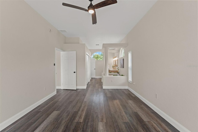 empty room with ceiling fan, dark wood finished floors, and baseboards