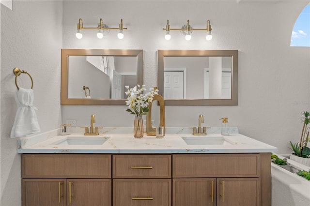 full bath with double vanity and a textured wall