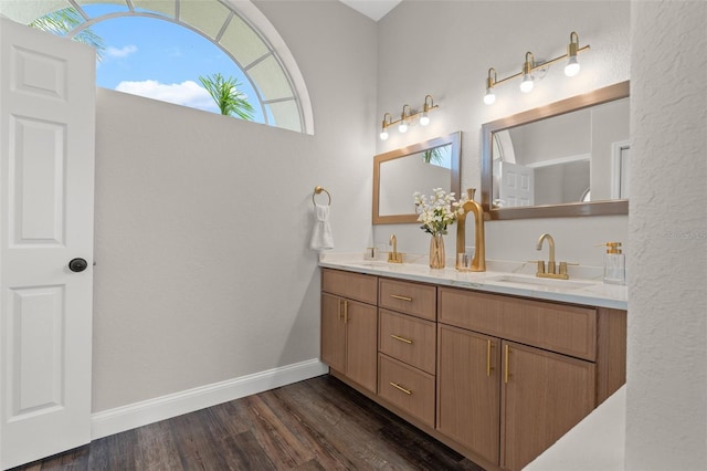 full bath featuring double vanity, wood finished floors, and baseboards