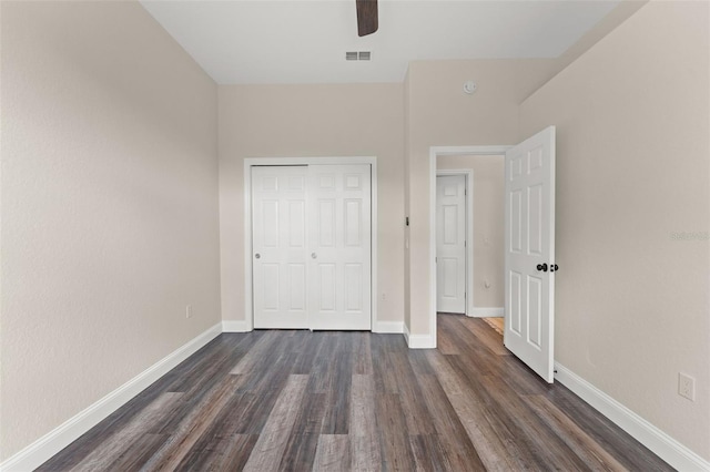 unfurnished bedroom with dark wood finished floors, a closet, baseboards, and ceiling fan