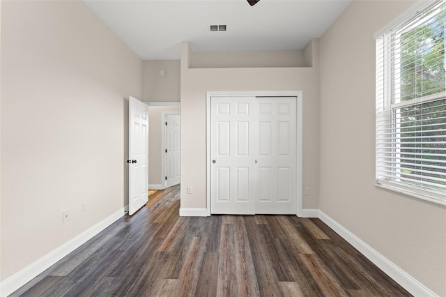unfurnished bedroom with dark wood-type flooring, baseboards, and a closet