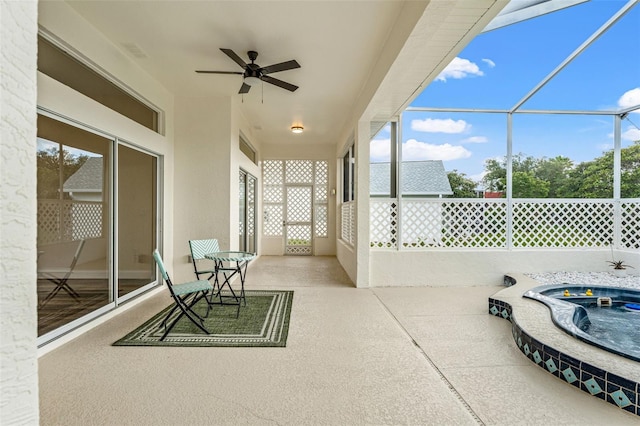 unfurnished sunroom with ceiling fan and a jacuzzi