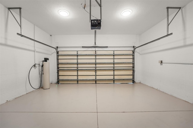 garage with a garage door opener and concrete block wall