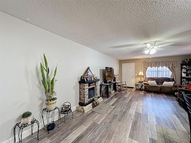 6213 Emerson Dr, New Port Richey, FL 34653 - living area with wood finished floors, a ceiling fan, a stone fireplace, a textured ceiling, and baseboards