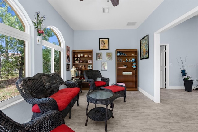 living area with a ceiling fan, wood finished floors, and baseboards