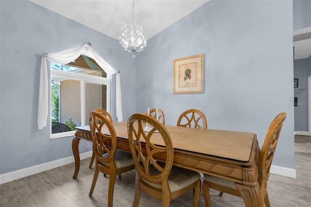 dining room featuring light wood finished floors, a chandelier, and baseboards