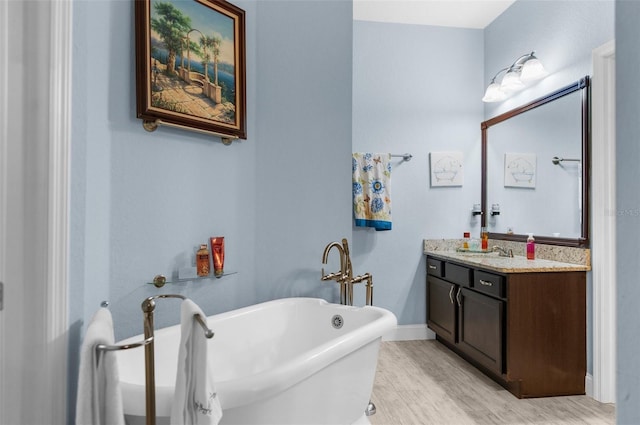 bathroom with vanity, a soaking tub, wood finished floors, and baseboards