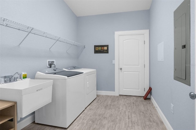 laundry area featuring electric panel, separate washer and dryer, light wood-style floors, and baseboards