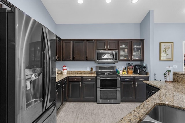 kitchen featuring stainless steel appliances, light wood-style flooring, light stone counters, dark brown cabinetry, and recessed lighting