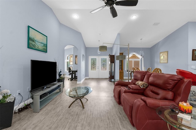 living area with arched walkways, ceiling fan, french doors, wood finished floors, and high vaulted ceiling