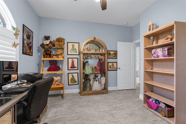 office area with a ceiling fan, wood finished floors, and baseboards