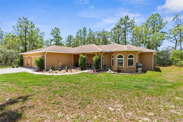 view of front of house with stucco siding, a garage, a front lawn, and driveway