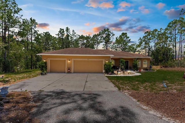 ranch-style home featuring a garage, driveway, a lawn, and stucco siding
