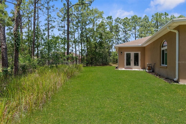 view of green lawn with french doors