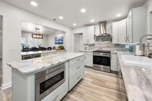 1620 Sea Breeze Dr, Tarpon Springs, FL 34689 - kitchen featuring wall chimney exhaust hood, appliances with stainless steel finishes, a sink, tasteful backsplash, and recessed lighting