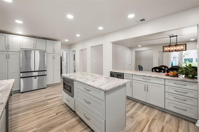 1620 Sea Breeze Dr, Tarpon Springs, FL 34689 - kitchen featuring appliances with stainless steel finishes, light wood finished floors, light stone countertops, a center island, and recessed lighting