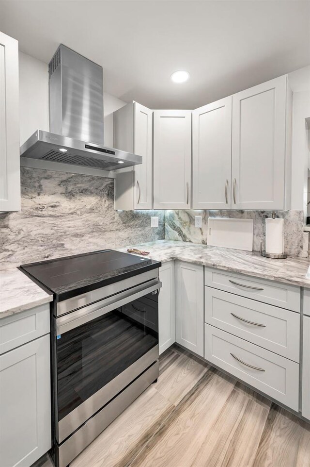1620 Sea Breeze Dr, Tarpon Springs, FL 34689 - kitchen with electric stove, wall chimney range hood, backsplash, light wood-style floors, and recessed lighting