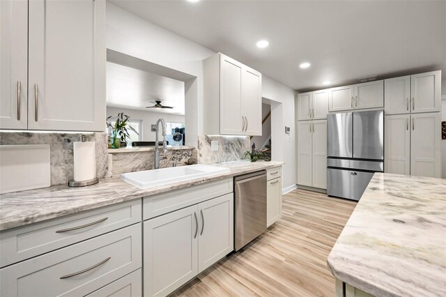 1620 Sea Breeze Dr, Tarpon Springs, FL 34689 - kitchen with appliances with stainless steel finishes, a sink, a ceiling fan, light wood finished floors, and backsplash