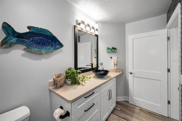 1620 Sea Breeze Dr, Tarpon Springs, FL 34689 - bathroom with vanity, toilet, wood finished floors, and baseboards