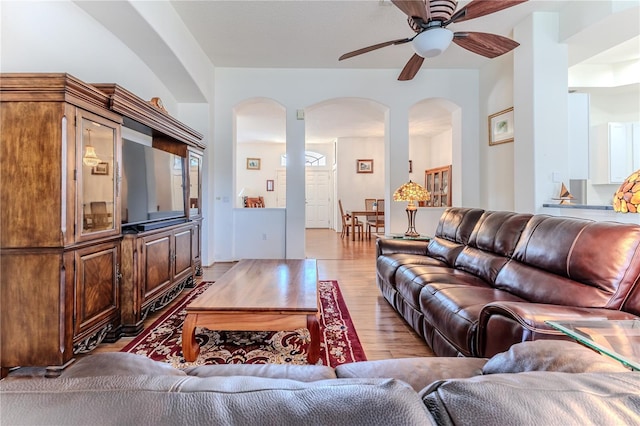 living room featuring arched walkways, wood finished floors, and ceiling fan