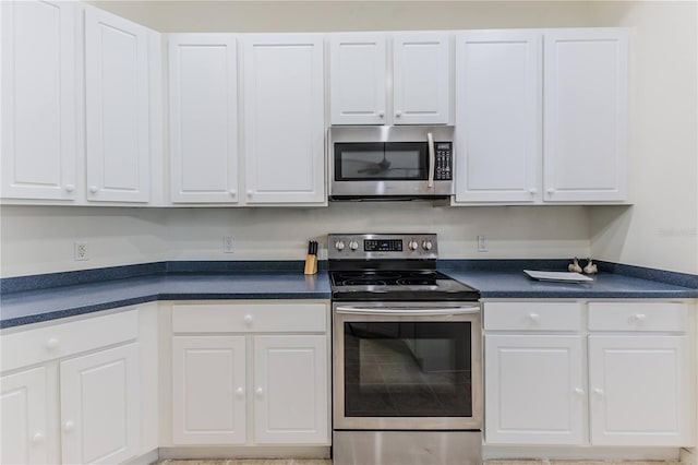 kitchen featuring appliances with stainless steel finishes, dark countertops, and white cabinetry
