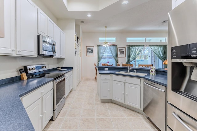 kitchen featuring appliances with stainless steel finishes, a sink, dark countertops, white cabinetry, and recessed lighting