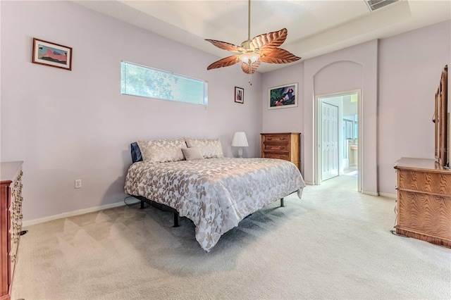 bedroom with light carpet, baseboards, a ceiling fan, and ensuite bath
